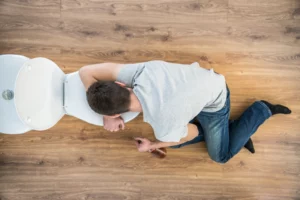 man laying on toilet with alcohol in his hand